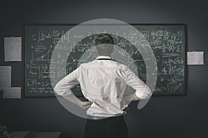 Mathematician solving problems and writing formulas on the chalkboard