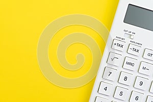 Mathematics, tax calculation, finance or investment concept, white clean calculator on solid yellow background with copy space photo