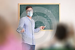 Mathematics teacher protected with mask explaining in class