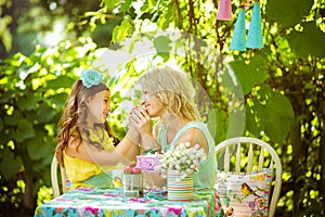 A mather and daughter hold hands and look to each other in the garden