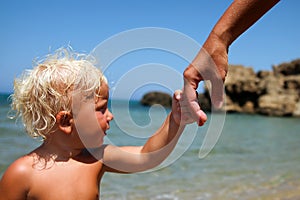 Mather holds the hand of a small child on a blue background