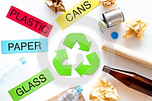 Matherials suitable for recycle near green recycle eco symbol. Words paper, glass, plastic, cans on white background top