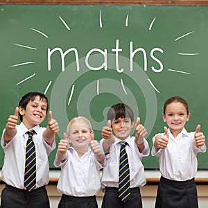 Maths against cute pupils showing thumbs up in classroom