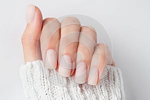 Matt nude nails close up on the light background. Winter manicure, woman hand in the warm sweater photo