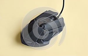 Matte modern black gaming mouse with buttons on a light yellow background