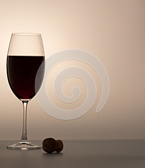 Matte wineglass half red wine cork on table