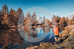 Matterhorn mountain with golden pine forest reflection in autumn at Grindjisee lake, Switzerland