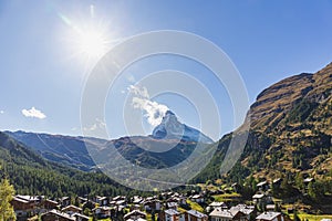 The Matterhorn mountain peak and valley with Zermatt village switzerland in summer under sun glare and blue sky background