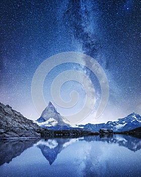 Matterhorn and reflection on the water surface at the night time. Milky way above Matterhorn, Switzerland.