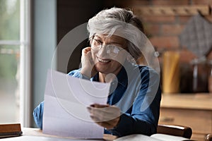 Mature 60s woman read paper postal correspondence at home