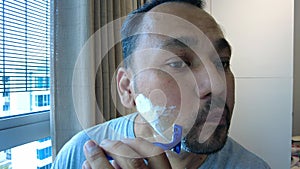 Mature adult asian metrosexual man shaving with razor on face. Goatee fashion suitable for fatherhood