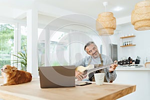 Mature Adult Male wearing apron playing acoustic guitar, Man with dog