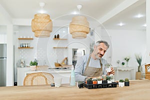 Mature Adult Man caring cactus at home