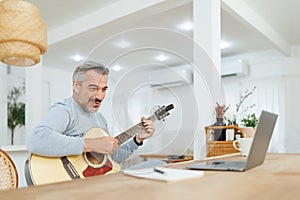 Mature Adult Man teaching acoustic guitar with video call