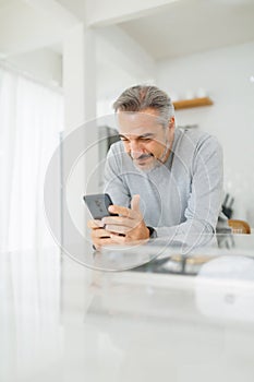 Mature Adult man using mobile phone at home