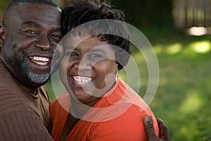 Mature African American couple laughing and hugging.