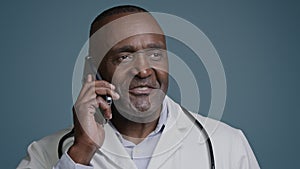 Mature african american male doctor consultant talking on mobile phone in blue background studio man specialist