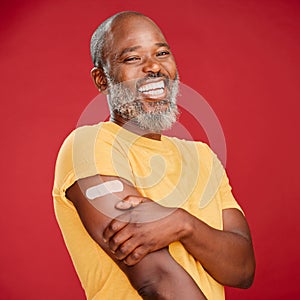 Mature african american man with a beard smiling and looking happy while wearing a bandaid and holding his arm and