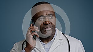 Mature african american man doctor talk on phone with patient close-up puzzled male medical consultant in white coat