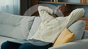 Mature african american man relaxed businessman freelancer resting on couch with hands behind head distracted from work