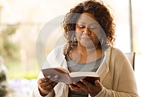 Mature African American woman sitting outside reading.