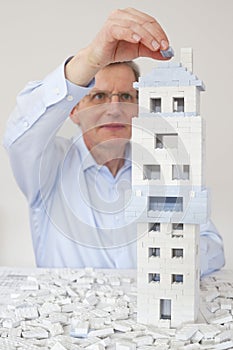 Mature architect constructing a house of toy blocks photo