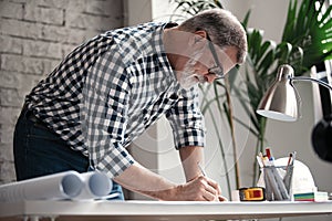 Mature Architect Engineer Design Working Planning Concept. Portrait of businessman working on blueprints at the office
