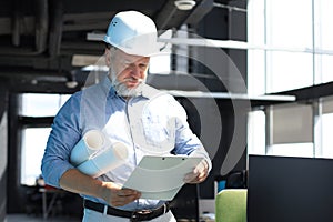 Mature architect wearing hardhat inspecting new building