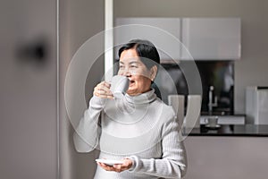 Mature asian woman drinking coffee near the window in the morning,Happy and smiling,Positive thinking,Health care senior insurance