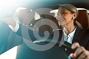 Mature asian woman looking in rear-view mirror while driving car