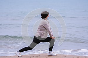 Mature asian woman stretching on the beach