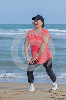 Mature asian woman stretching on the beach
