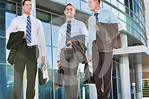 Mature attractive businessmen walking while talking against office building after work