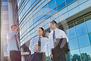 Mature attractive businessmen walking while talking against office building after work