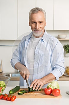 Mature attractive man standing at the kitchen cooking