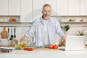 Mature attractive man standing at the kitchen cooking