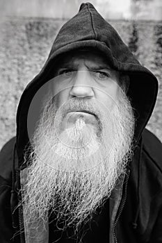 Mature bald man with long gray beard wearing hoodie outdoors