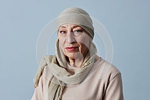 Mature bald woman wearing headscarf looking at camera