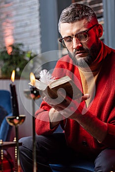 Mature bearded future predictor reading old little book for magicians