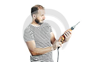 Mature bearded handyman looking at the drill machine in his hand with a questioning look.