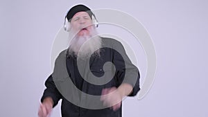 Mature bearded hipster man dancing while listening to music
