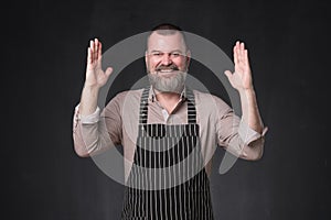 Mature bearded man in apron bragging about the big size of something. photo