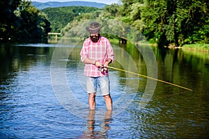 Mature bearded man with fish on rod. big game fishing. relax on nature. successful fisherman in lake water. hipster