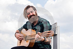 mature bearded man looking casual trendy playing guitar, guitarist