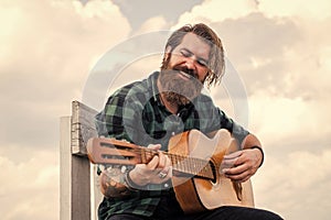 mature bearded man looking casual trendy playing guitar, guitarist