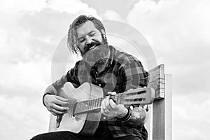 mature bearded man looking casual trendy playing guitar, guitarist