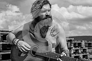 mature bearded man looking casual trendy playing guitar, musician