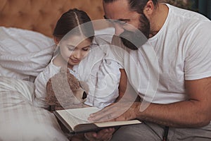 Mature bearded man resting at home with his little daughter