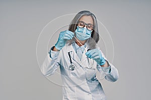 Mature beautiful female doctor in face mask holding medical test