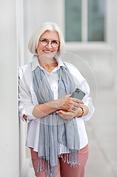 Mature beautiful professional business woman with smartphone, happy confident positive model entrepreneur standing